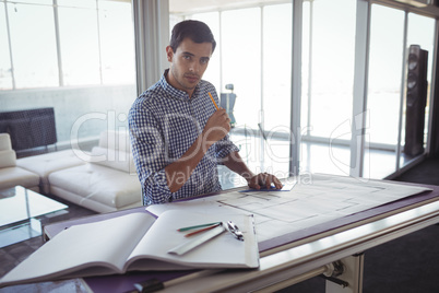 Young male interior designer planning on paper in office