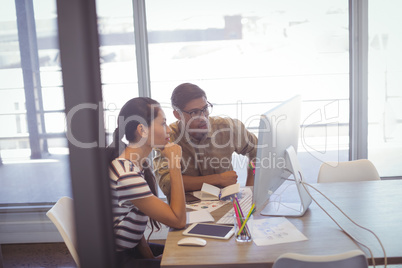 Businessman and businesswoman discussing over computer