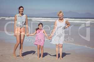 Portrait of happy multi-generation family holding hands at beach