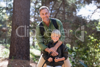 Happy father and son standing against trees in forest