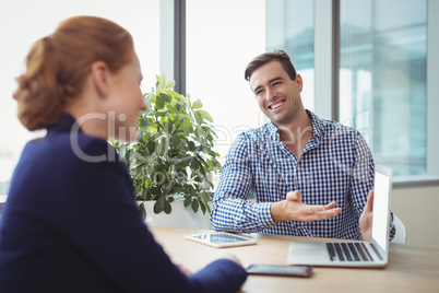 Executives discussing over laptop at desk