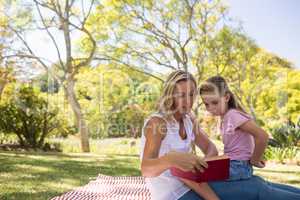 Mother and daughter reading novel in park