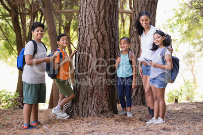 Happy students and teacher standing by tree