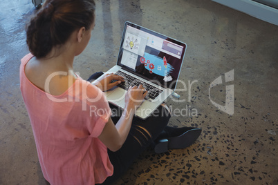 Graphic designer working on laptop while sitting at floor