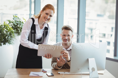 Portrait of executives using laptop at desk