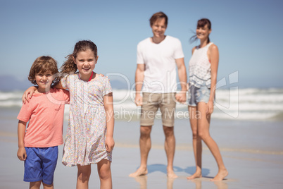 Portrait of smiling siblings standing with parents in background