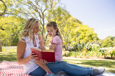 Mother and daughter reading novel in park