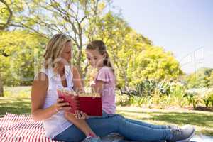 Mother and daughter reading novel in park