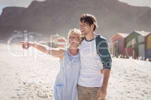 Happy woman pointing away with her son standing at beach
