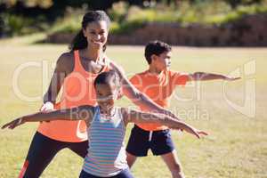 Portrait of trainer and girl practicing Virabhadrasana II pose