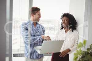 Executives shaking hands while using laptop