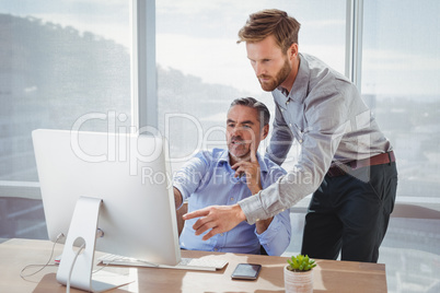 Executives discussing over personal computer at desk