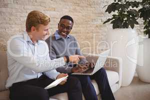 Smiling executives discussing over laptop