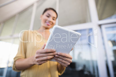 Low angle view of smiling businesswoman using tablet in office