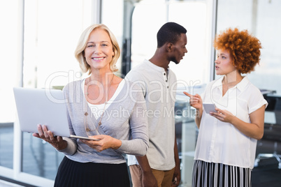 Portrait of mature businesswoman with colleagues in background