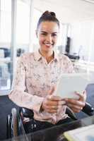 Portrait of smiling businesswoman using digital tablet while sitting on wheelchair