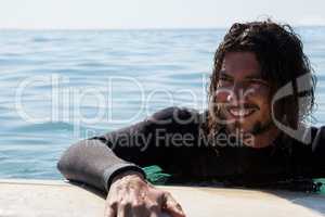 Surfer leaning on surfboard in sea