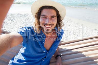 Man taking selfie while relaxing on hammock