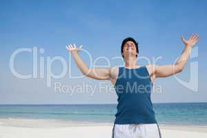 Man standing at beach with arms outstretched