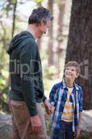 Smiling boy and father looking at each other in forest