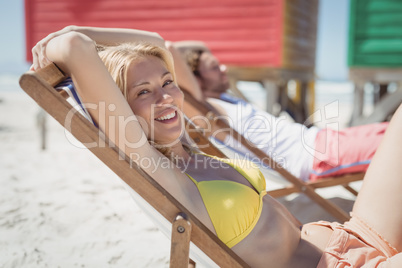 Portrait of young woman relaxaing on lounge chair at beach
