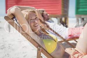 Portrait of young woman relaxaing on lounge chair at beach