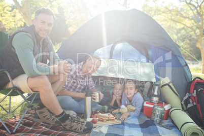 Smiling family having snacks outside the tent on a sunny day