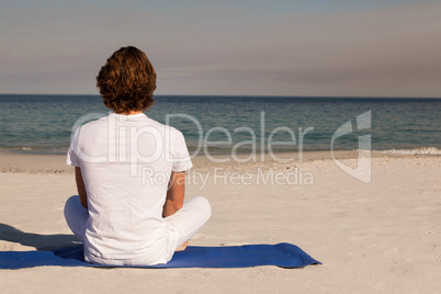 Rear view of man meditating at beach