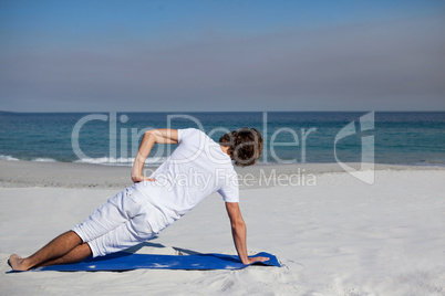 Man performing yoga at beach