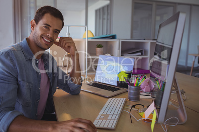 Portrait of smiling businessman sitting at creative office