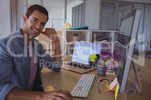 Portrait of smiling businessman sitting at creative office