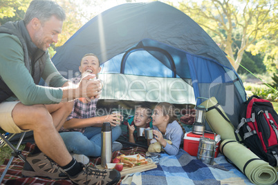 Family interacting while having snacks outside the tent