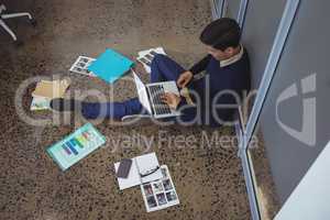 Businessman sitting on floor while working in creative office