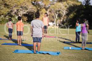 Children standing on exercise mat practicing yoga