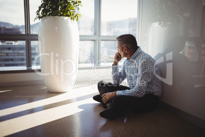 Thoughtful executive sitting on floor