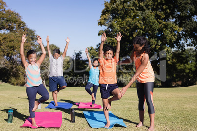 Trainer examining kids practicing yoga