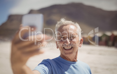 Happy senior man taking selfie at beach