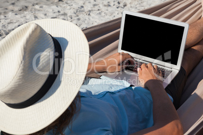 Man using laptop while relaxing on hammock
