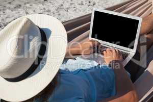 Man using laptop while relaxing on hammock