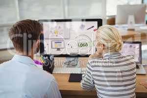 Attentive graphic designers working over personal computer at desk