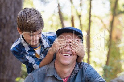 Boy covering fathers eyes in forest