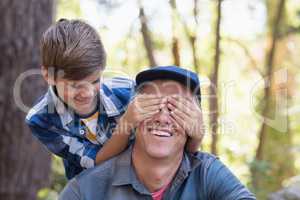 Boy covering fathers eyes in forest