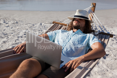 Man with laptop relaxing on hammock