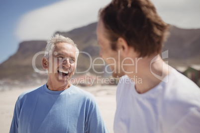 Cheerful senior man with his son standing at beach
