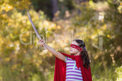 Little girl holding sword while wearing superhero costume