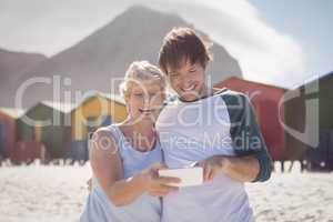 Happy mother with son using mobile phone at beach