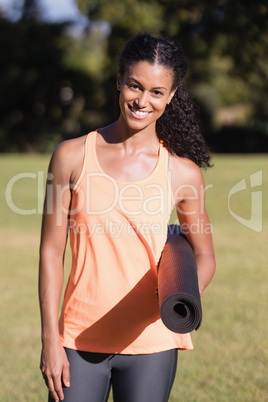 Portrait of happy woman holding exercise mat