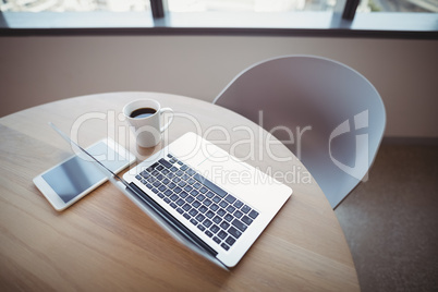 Cup of coffee with digital tablet and laptop on table