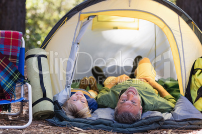 Smiling father and son lying in tent at campsite