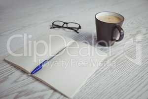 Pen and book with coffee cup on table